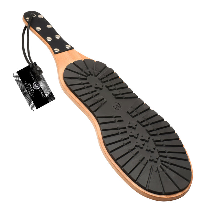 A BDSM paddle with a rugged black rubber boot sole on one side and smooth polished wood on the other, featuring a vegan leather-wrapped handle and hanging loop.