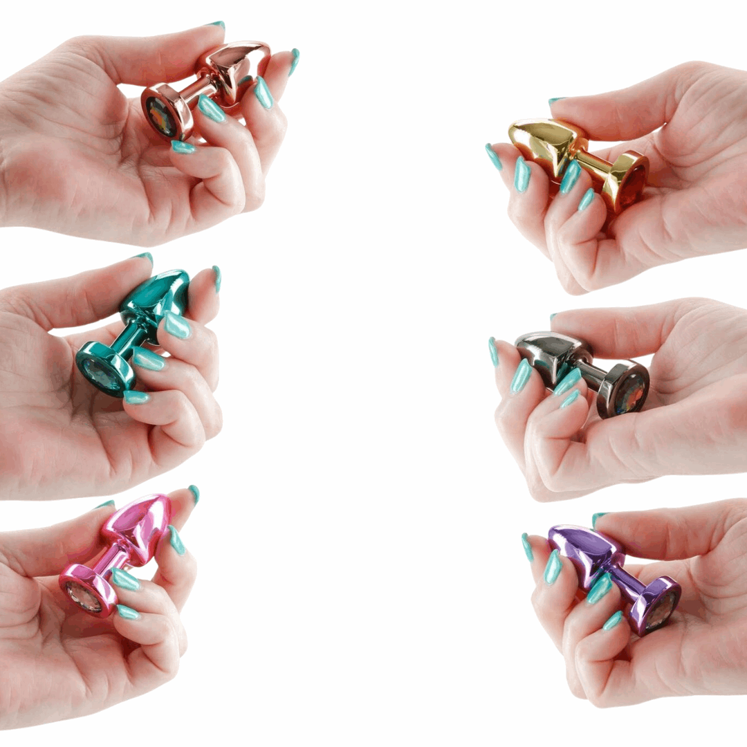 Multiple hands holding Rear Assets anal plugs in different metallic colors, showcasing their lightweight design and jeweled bases.