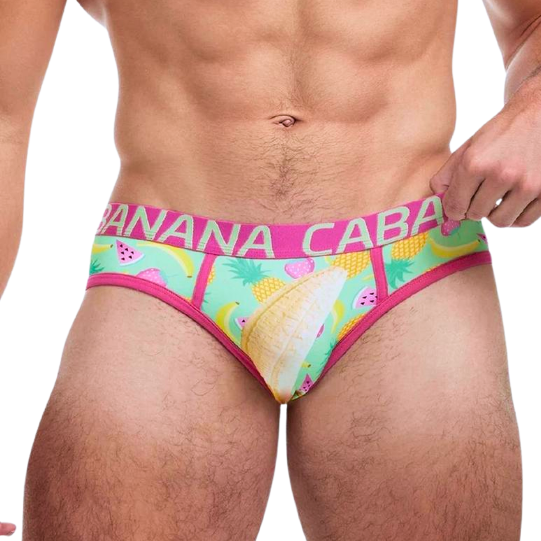 Brazilian bikini briefs with a tropical fruit salad print featuring bananas, pineapples, strawberries, and watermelon slices, and a bold pink Banana Cabana waistband.

