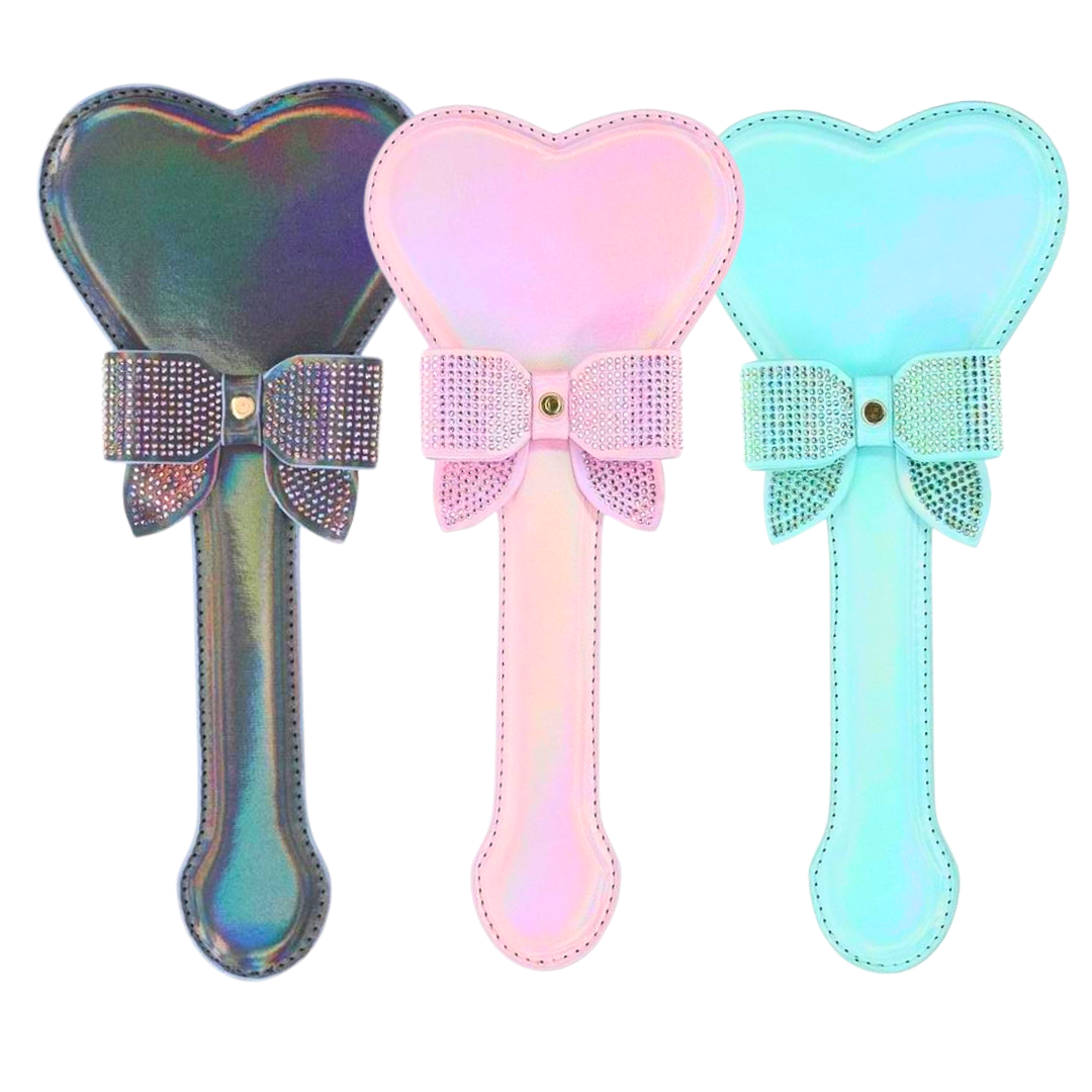 Heart-shaped paddle with iridescent hardware and rhinestone bow, available in black, pink, and blue for decorative or BDSM use.