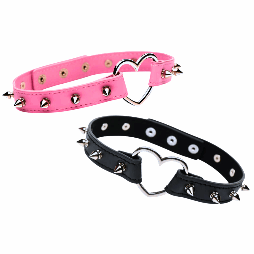 Spiked vegan leather collar with heart accent, adjustable snaps, and nickel-free hardware, available in light pink or black.