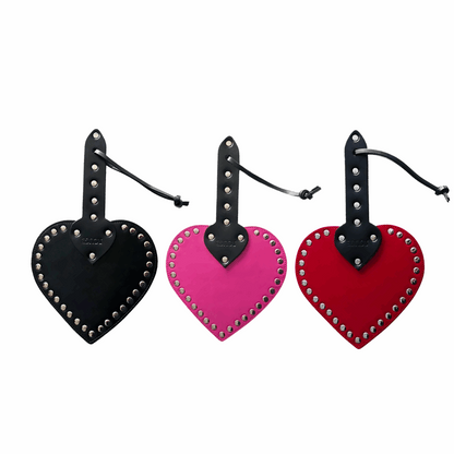 Heart-shaped leather spanking paddle with riveted studs, wrist strap, and genuine cowhide leather in pink, black, or red.

heart-shaped paddle, leather spanking paddle, genuine leather paddle, impact play paddle, heart impression paddle, luxury bondage paddle, studded spanking paddle, pink leather paddle, black leather paddle, red leather paddle, handcrafted BDSM paddle.