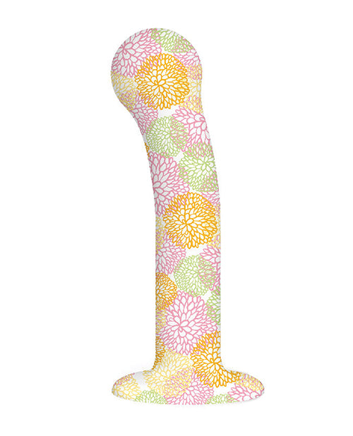 Item shown out of package. 7 inch dildo with pink, orange, yellow, green flowers painted on. White backdrop. Suction cup and flared base. Non-anatomical in nature, rounded tip with curved shaft. No detailing involving skin or balls.