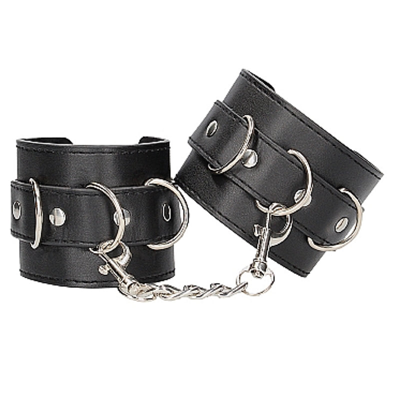 Black leather cuffs. Silver metal detailing. Numerous D rings around the cuffs with metal ribbons. Attached via a chain.